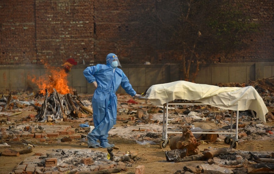  A Family member, wearing a Personal Protective Equipment (PPE), waits to perform the last rites for COVID-19 victims at a cremation ground in New Delhi, India. - EPA pic