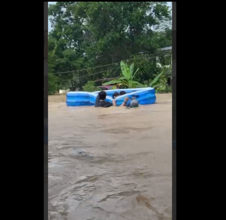 A video grab showing residents using an inflatable to rescue children during a flood in Penampang today. -- Pic from socmed