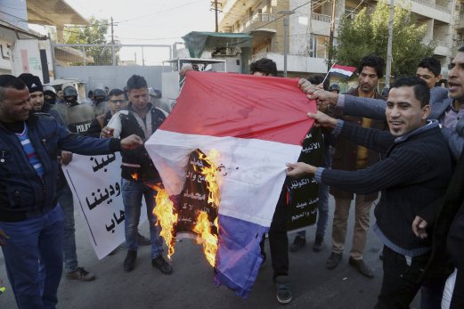 Iraqi demonstrators chant angry slogans as they set a French flag on fire during a protest against caricatures of the Prophet Muhammad published in the satirical French weekly magazine Charlie Hebdo, outside the French Embassy in Baghdad, Iraq. AP Photo.