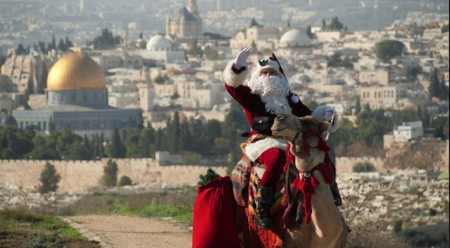 Issa Kassissieh, dressed as Santa Claus, riding a camel in Jerusalem. - REUTERS PIC