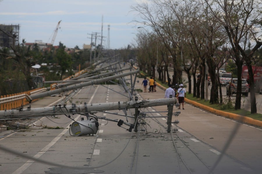  Residents walk past downed electric pylons in Talisay town, Cebu province on December 17, 2021, a day after Super Typhoon Rai pummelled the southern and central regions of the Philippines. -AFP PIC 