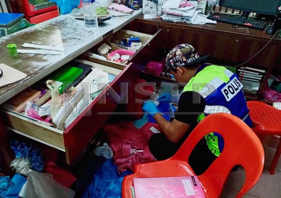 A policeman inspects the crime scene after eight armed men robbed a sundry shop in Sungai Bidut, Sibu. - NSTP/HARUN YAHYA