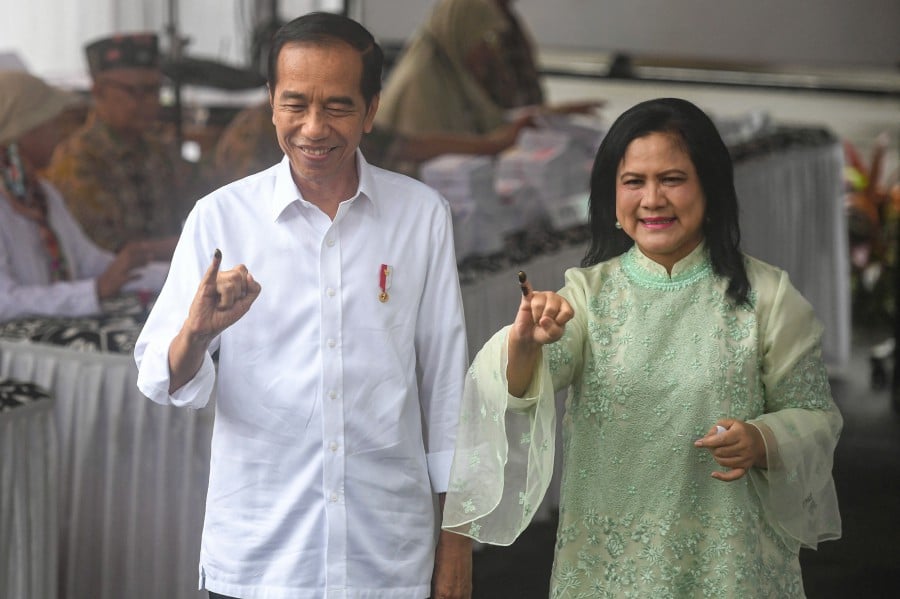 President Joko Widodo and First Lady Iriana show their inked fingers after casting their ballots at a polling station during the general election in Jakarta, Indonesia. - REUTER PIC