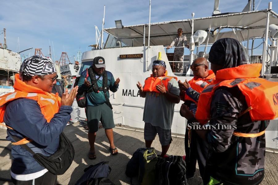 Those rescued, offer prayers upon reaching safely at the  MMEA jetty in Kuala Terengganu. - NSTP/GHAZALI KORI