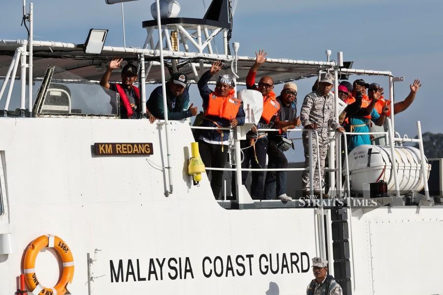 Those rescued wave at their family members while onboard MMEA vessel in Kuala Terengganu.  - NSTP/GHAZALI KORI