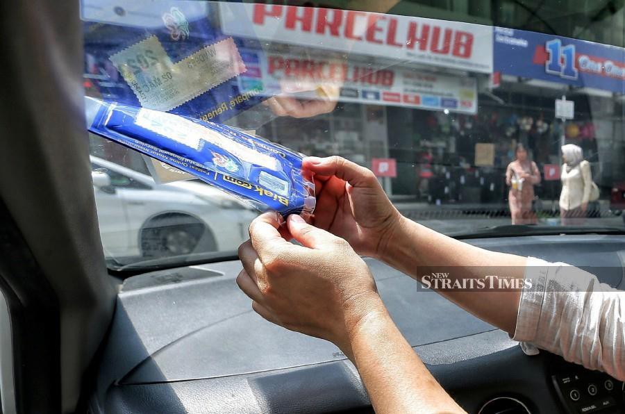 A motorist removes the road tax following the announcement made by Transport Minister Anthony Loke, earlier today. - NSTP/ SAIFULLIZAN TAMADI