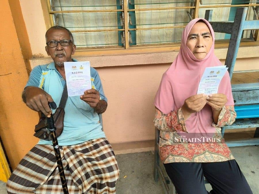 Asiah Rani with her husband Mohamad Salleh showing their PPS cards. -NSTP/Sharifah Mahsinah Abdullah