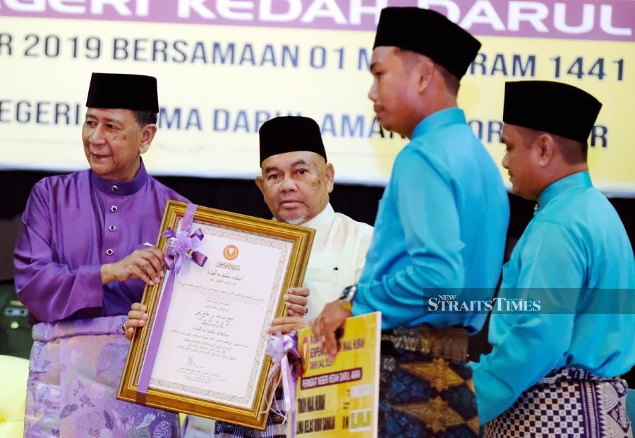 Sultan of Kedah Sultan Sallehuddin Sultan Badlishah (left) presents the state’s Tokoh Maal Hijrah award to Abdullah Yahaya during the state-level Maal Hijrah celebration at Wisma Darul Aman. -NSTP/Amran Hamid