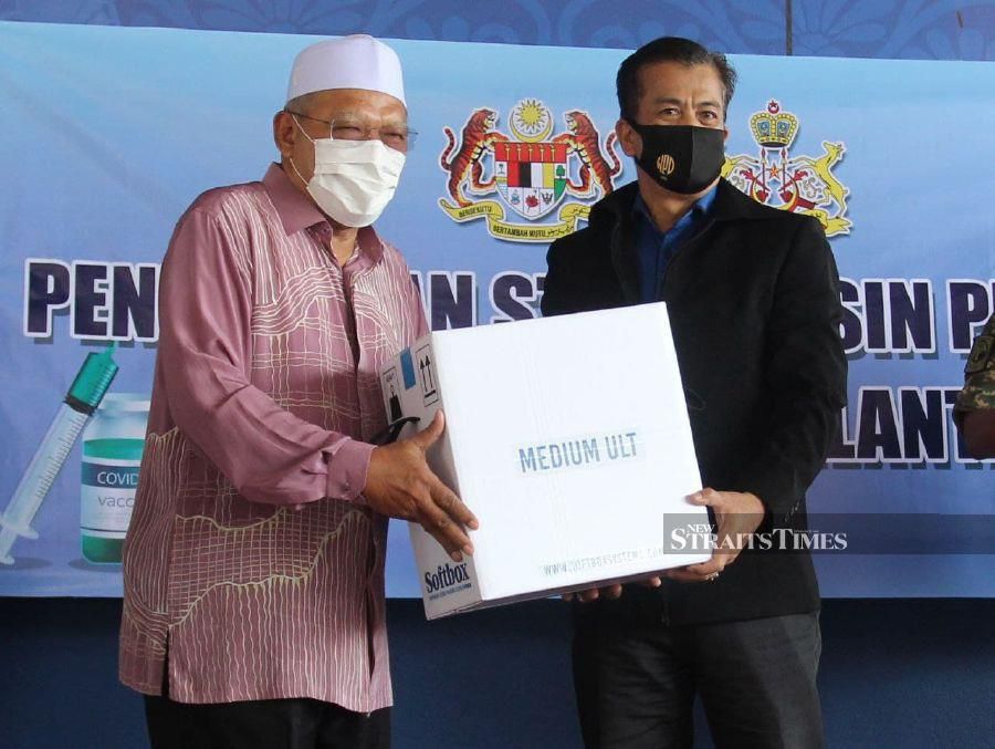 Kelantan Menteri Besar Datuk Ahmad Yakob (left) handing over the Covid-19 vaccine to state health director Datuk Dr Zaini Hussin at  the state police headquarters in Jalan Bayam. - NSTP/NIK ABDULLAH NIK OMAR