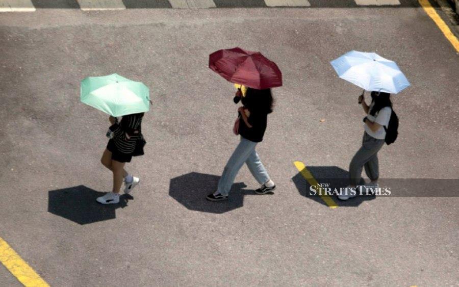 KUALA LUMPUR, March 19 — Students using umbrellas to shield themselves from the hot weather at Tunku Abdul Rahman University of Management and Technology. -NSTP/MOHAMAD SHAHRIL BADRI SAALI. 