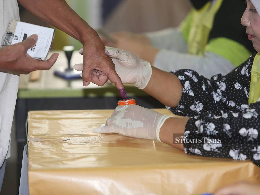 A voter dips his index finger in the indelible ink before casting his vote at Dewan Serbaguna dan Kompleks Sukan Daerah Hulu Selangor. - NSTP/SAIFULLIZAN TAMADI