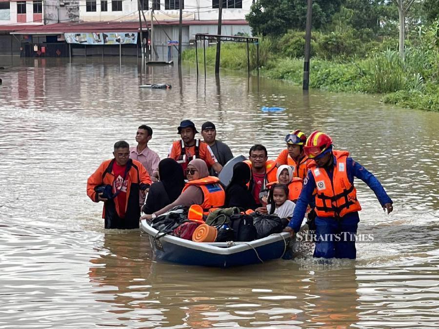 Firemen utilise a boat to rescue flood victims in Taman Kemang, Kota Tinggi. -NSTP/NUR AISYAH MAZALAN