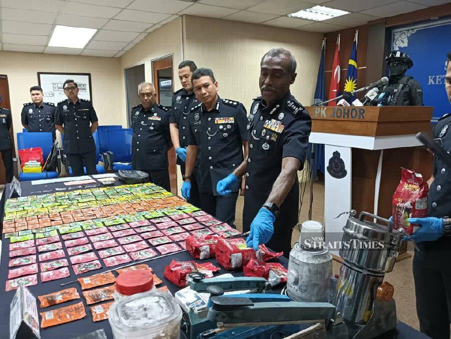 Johor police chief Commissioner M. Kumar (right) showing the drug-laced juice packets seized during raids in Johor Baru and Seri Alam.