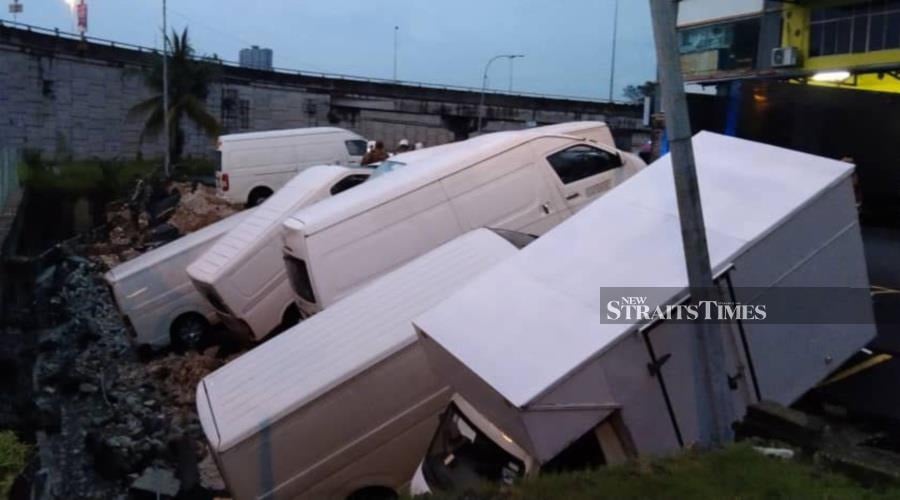 The incident happened around 6.35pm where the soil in between the elevated highway and the parking lots caved in, affecting six vans and one lorry. - Pic courtesy of Fire and Rescue Dept