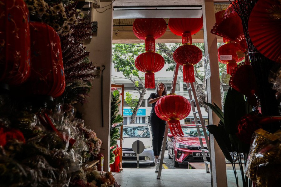KUALA TERENGGANU: Emily Lim Huey Lan installing lanterns at her shop in preparation for the Chinese New Year celebration in Kampung Ladang, Kuala Terengganu. -- NSTP/GHAZALI KORI