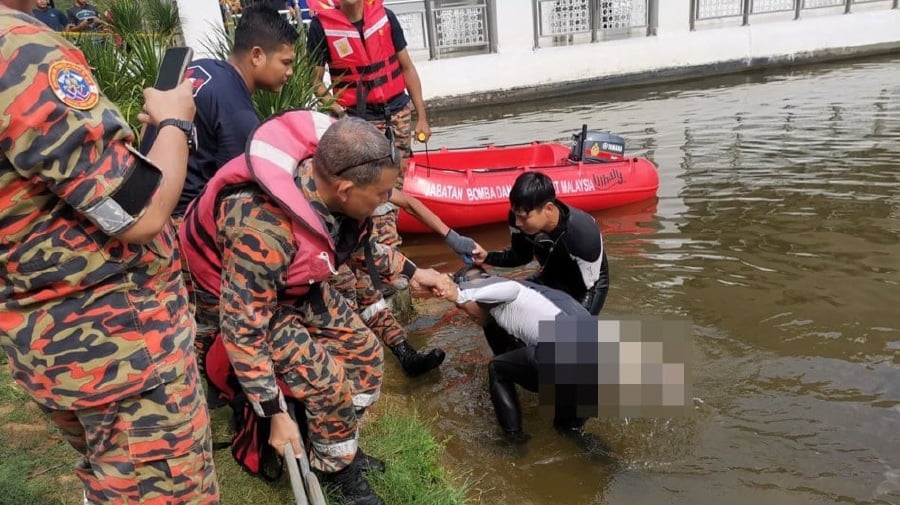 Rescuers pulling the body of the boy out of the lake near the Universiti Teknologi Petronas (UTP) mosque. -- Pic from Fire and Rescue Dept