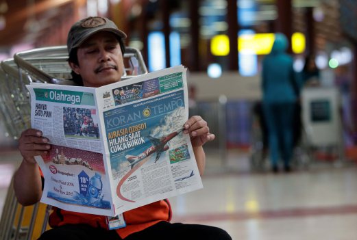 Ude Hermawan 40, reads a local newspapers at the Soekarno-Hatta International Airport. Pix by AIZUDDIN SAAD