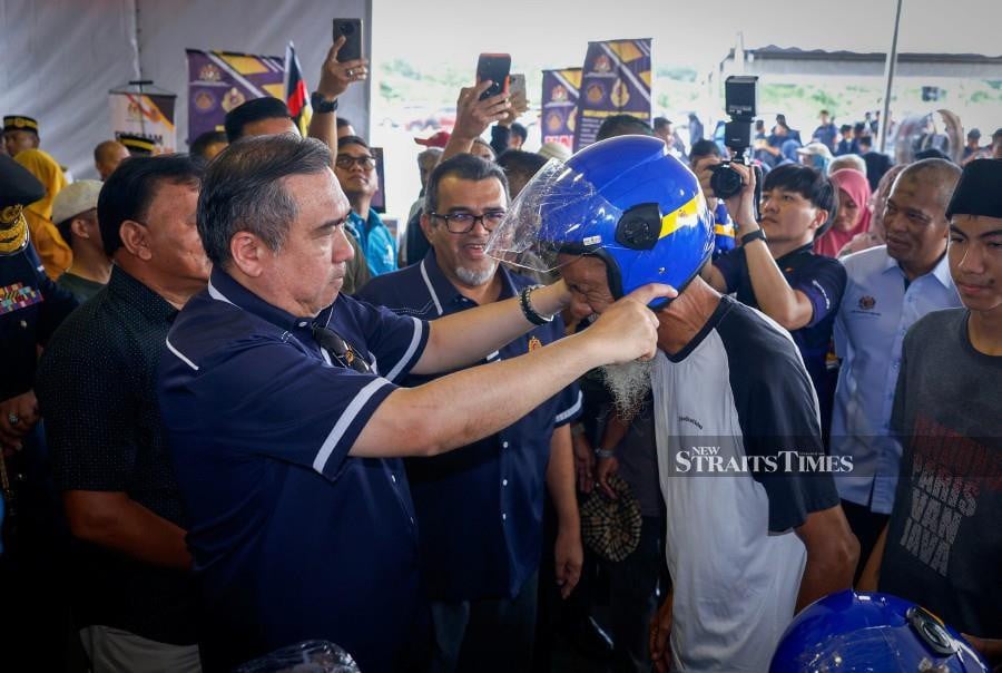 Transport Minister Anthony Loke puts a helmet on a man at the Road Transport Department Day Anniversary Celebration at the Malaysian Road Transport Academy in Melaka in Ayer Molek, Melaka today.— fotoBERNAMA (2024) HAK CIPTA TERPELIHARA