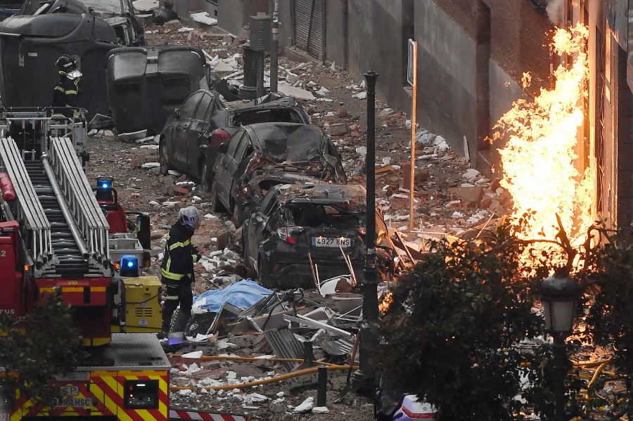  Firefighters walk outside a building in Madrid after a strong explosion rocked it. - AFP pic