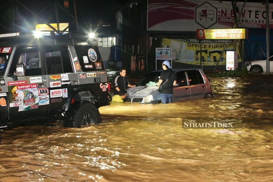 Members of the MH4x4 Club helping to pull a car stranded during the flood in Jalan Penampang tonight. STR/MOHD ADAM ARININ