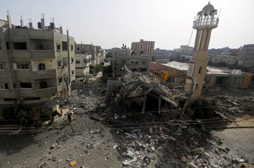 Palestinians walk around the ruins of the Al-Tawfeeq Mosque after it was hit by an overnight Israeli missile strike in the Nuseirat refugee camp, central Gaza Strip, Saturday, July 12, 2014. Israeli airstrikes targeting Hamas in Gaza hit a mosque its military says concealed the militant group's weapons, as the Palestinian death toll topped 120 Saturday in an offensive that showed no signs of slowing down. AP Photo