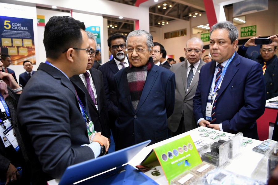 Prime Minister Tun Dr Mahathir Mohamad (second, left) listening to an explanation from Usaha Strategik Sdn Bhd Executive Director Za'im Hadi Meskam (left) during a visit to the Malaysian Pavilion in conjunction with the ASEAN Invest Exhibition. Also present is Foreign Minister Datuk Saifuddin Abdullah. - Bernama