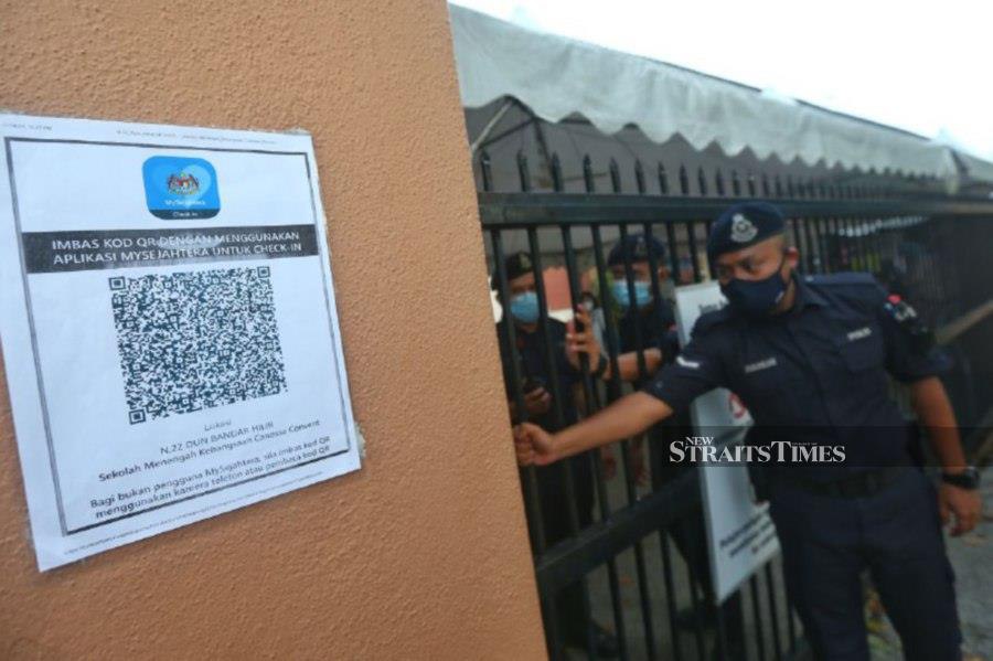 Police officers on duty closes the gate to the polling centre at SMK Cannosa Convent in Melaka. -NSTP/SYAFEEQ AHMAD