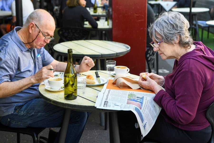 A couple enjoys breakfast at a busy Lygon Street cafe in Melbourne, following the midnight lifting of coronavirus restrictions in one of the world's most locked-down cities. - AFP PIC