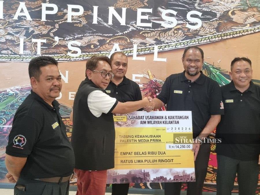 Kelantan AIM Region general manager Mohd Abu Samah Mohd Daud handing over a mock cheque to Kelantan MPB representative Shahnun Hanif Abdullah Suhaimi at a hotel in Kota Baru. - NSTP/Sharifah Mahsinah Abdullah
