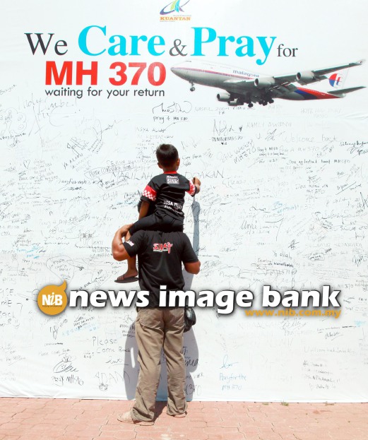 27 March 2014: M. Khairul Azhar, 31, helps his son Ahmad Irfan Firdaus, 4, to write a note in memory of flight MH370 at the Taman Teruntum Mini Zoo in Kuantan, Pahang. Pix by Halim Mat Ali