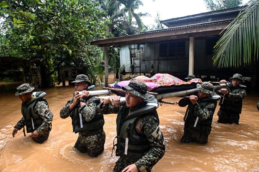 KUALA BERANG - Members of the Malaysian Armed Forces had to navigate through the floods to carry the remains of Kelthom Mat, 84, at her residence in Kampung Bukit Tadok here. - BERNAMA PIC