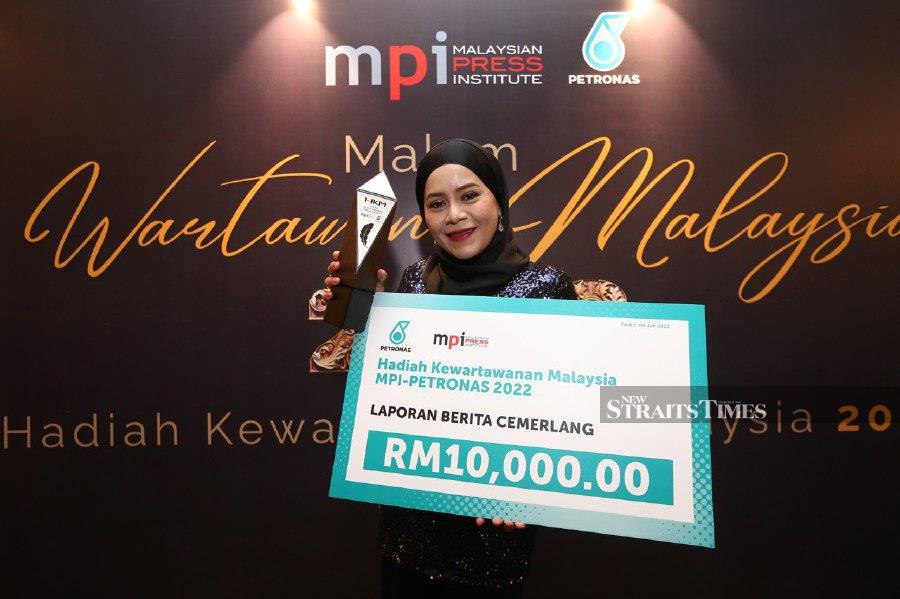 New Straits Times group editor Farrah Naz Karim poses with her trophy and a mock cheque. -NSTP/SAIFULLIZAN TAMADI