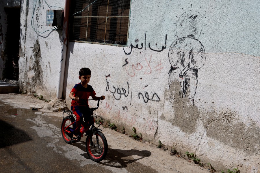 A Palestinian refugee child rides a bicycle next to a mural reading " Right of Return" taken before Nakba Day, on which Palestinians commemorates the 75th anniversary of the "Nakba" or catastrophe this year, in the Fara'a refugee camp in Palestine near Tubas in the Israeli-occupied West Bank. (REUTERS/Raneen Sawafta)