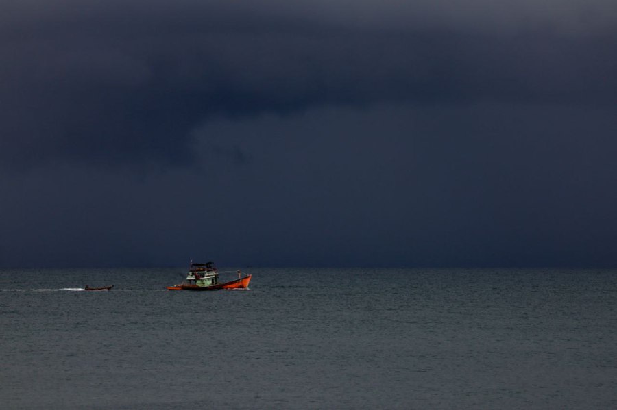  KUALA TERENGGANU: A fishing boat is overshadowed and dwarfed by the imposing dark and gloomy clouds up above which is an indication of the coming Northeast Monsoon at Pantai Seberang Takir here on Tuesday. -- BERNAMA PIC