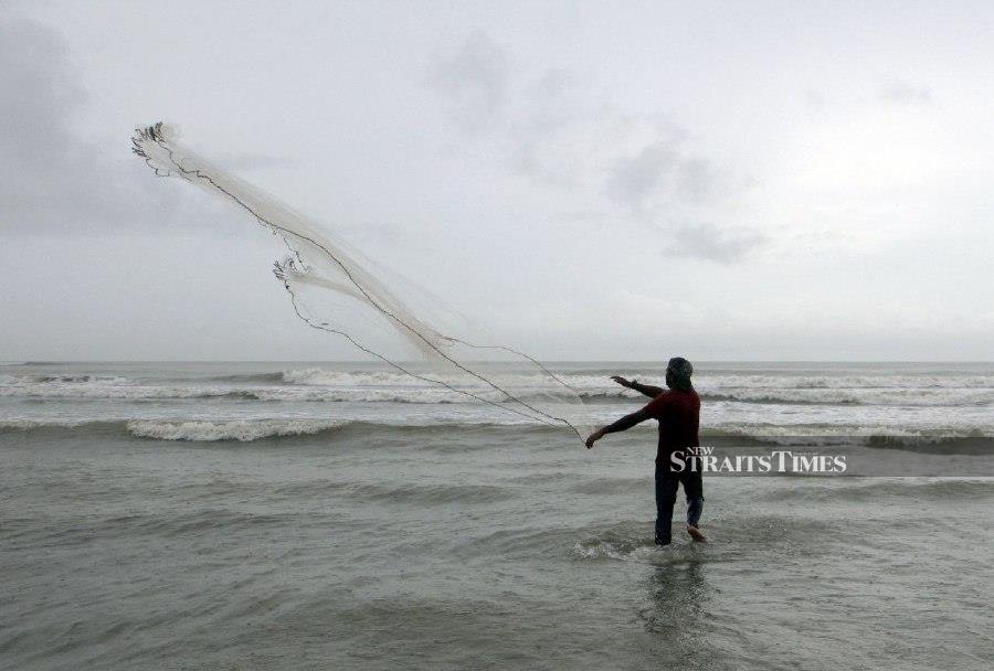 KUANTAN: A resident fishing using a net on a cloudy and windy day in Pantai Batu Hitam. - BERNAMA PIC