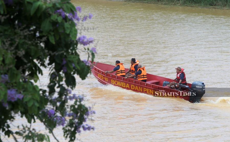  Firemen conduction a search and rescue mission to locate the man at Sungai Kelantan, in Kampung Kutan Sungai, Wakaf Bharu. -NSTP/NIK ABDULLAH NIK OMAR