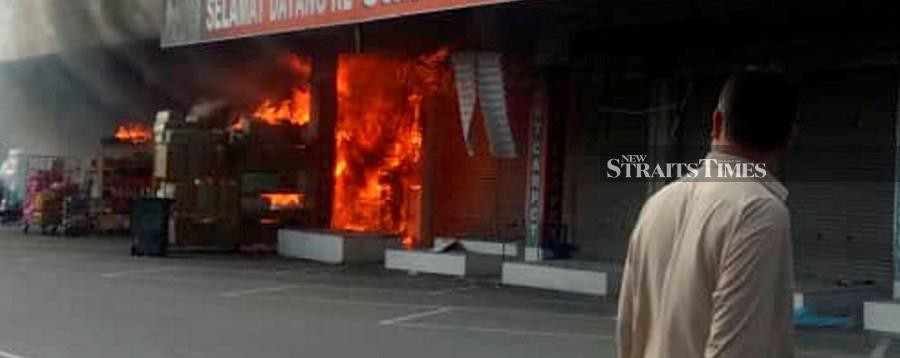 A man watched as fire engulfs a shop at the Nilai 3 Industrial Zone. -NSTP/Courtesy of Fire and Rescue Dept.