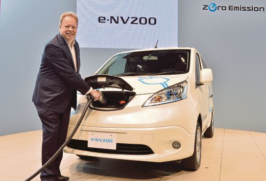 Chief planning officer for Japan's auto giant Nissan, Andy Palmer, poses with the company's new commercial electric vehicle "e-NV200" at the company's headquarters in Yokohama, suburban Tokyo on June 9, 2014. Nissan will put the Spanish-made new electric vehicle, which travel 190 kms per charge, on to the Japanese market in October. AFP PHOTO 