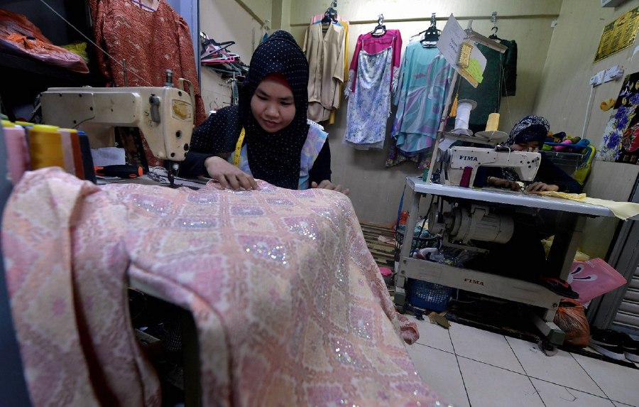 SHAH ALAM: Sharifah Ahmad (right) busy fulfilling orders for new clothes from customers in time for Hari Raya. -- BERNAMA PIC