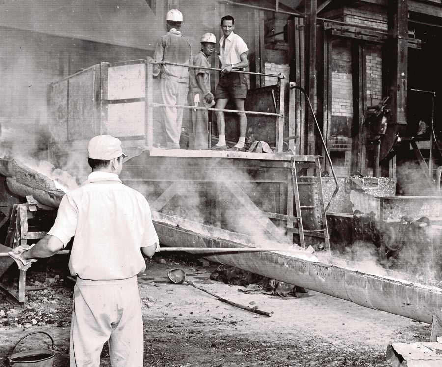  Workers inspecting pure molten tin flowing out from the furnace.