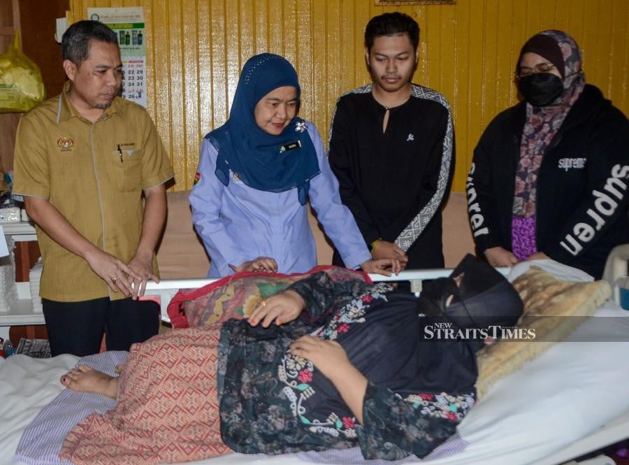  Kelantan Social Security Organisation (Socso) director Nora Yaacob (centre) visits Rosydiah Rashidi at the latter’s home in Kampung Manal Setia, Tanah Merah. - BERNAMA PIC