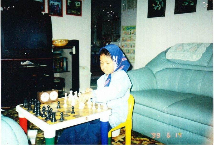 Young Alia playing chess before going to her kindergarten.