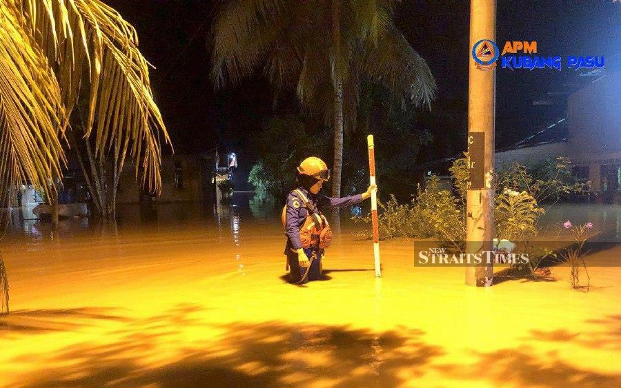 A Civil Defence Force personnel is seen measuring the water level following the floods in Kubang Pasu. - Courtesy pic