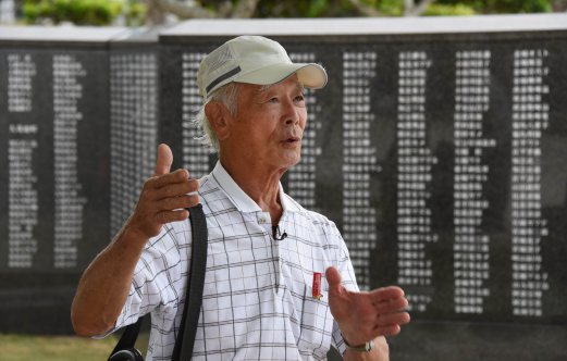  War survivor Zenichi Yoshimine tells his experiences beside a monument commemorating more than 240,000 people including US soldiers who died in the battle of Okinawa during World War II at the Peace Memorial Park in Itoman, Okinawa prefecture, on June 19, 2015. The battle claimed the lives of more than 100,000 Okinawan civilians and 80,000 Japanese troops, whose grim resistance only ended after Lieutenant General Mitsuru Ushijima, the senior officer on the island, committed ritual suicide on a cliff. AFP PHOTO 