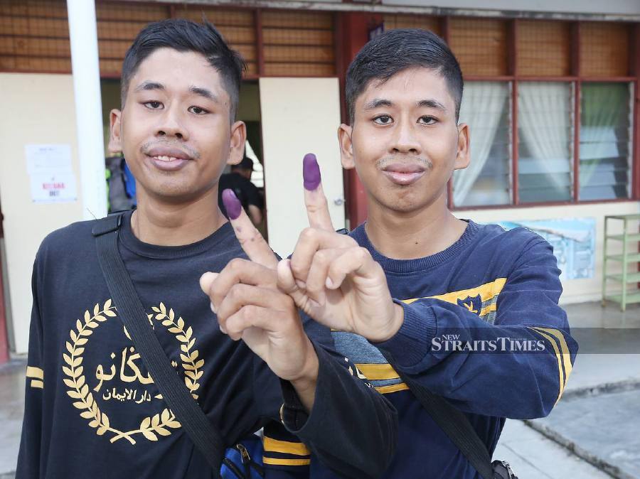 Muhammad Nazri Mohd Mazlan (left) and his twin brother Muhammad Nazmi, both who are OKU, cast their vote at SK Bandar Baru, Batang Kali. - NSTP/SAIFULLIZAN TAMADI