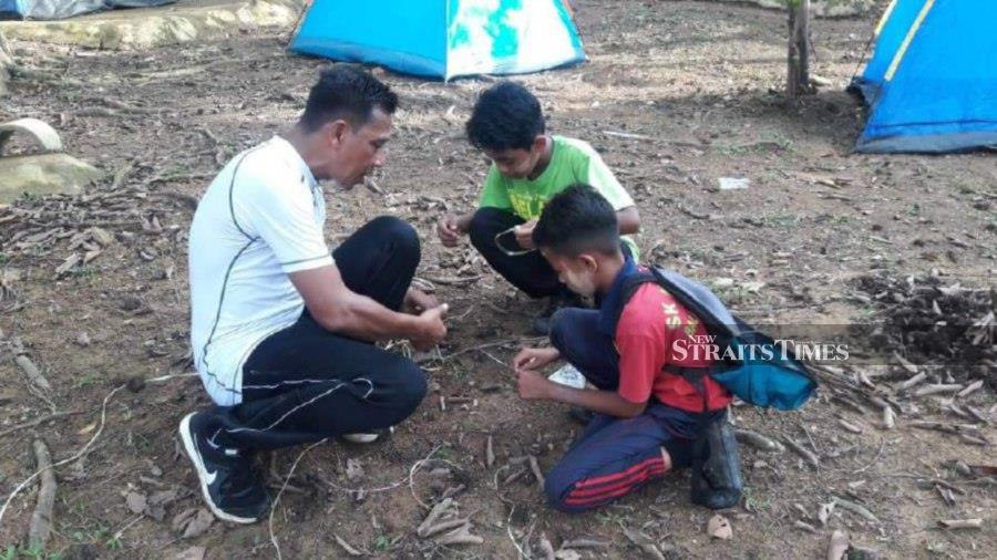 Azizuddin teaching the art of survival in the jungle to his students. - Pic by Rosli Zakaria