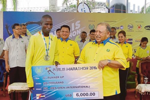 Raja Perlis Tuanku Syed Sirajuddin Putra Jamalullail presenting a mock cheque to Kennedy Kiproo of Kenya, who won the full marathon (men’s international) category in Kangar yesterday. Bernama Photo 