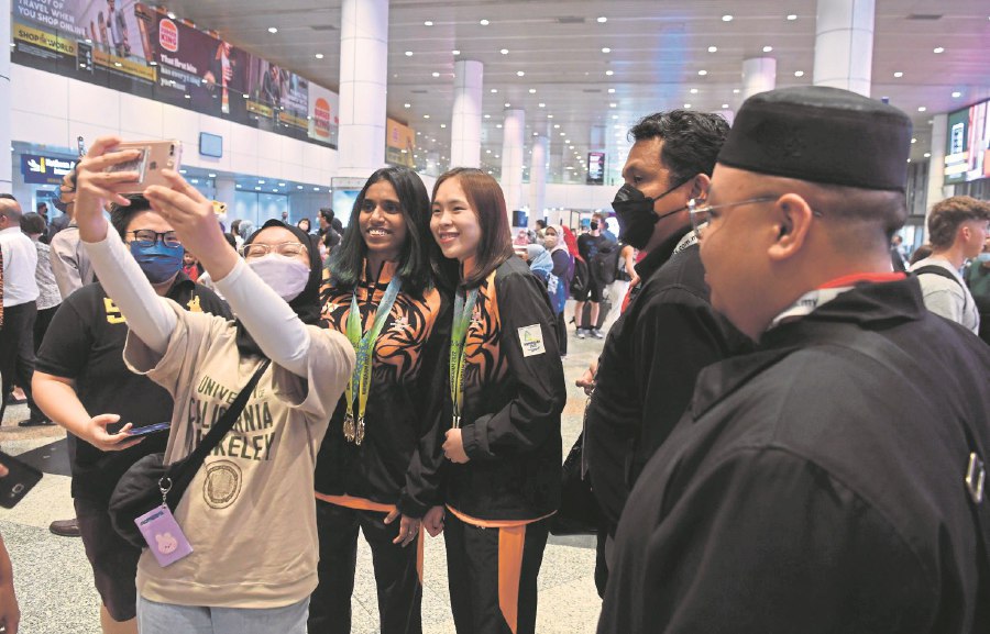 Pearly Tan (third from right) and M. Thinaah pose for pictures with fans at KLIA after arriving from Birmingham on Wednesday. -- BERNAMA PIC