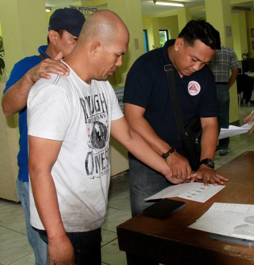 This handout photo taken on June 11, 2014 and released by the Philippine National Police shows senior Philippine Islamic militant Khair Mundos (front L), on the US government's "most wanted" list, being fingerprinted by Philippine police after he was arrested in Manila following a manhunt lasting seven years. Mundos, who had a 500,000 USD US government reward on his head, was detained at 9.30am (0130 GMT) close to the capital's airport where he was staying with relatives, the police and military said after a joint raid. AFP PHOTOPHILIPPINES NATIONAL POLICE
