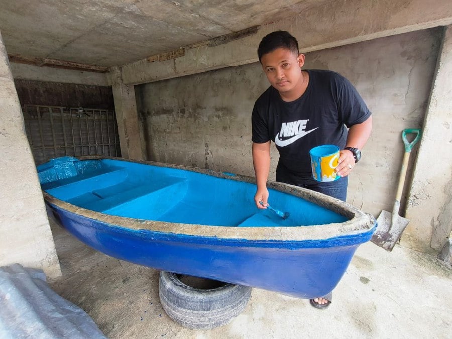 Mohamad Badrul Amin preparing a boat under his home and gearing up for the potential threat of floods. -- NSTP/SHARIFAH MAHSINAH ABDULLAH 